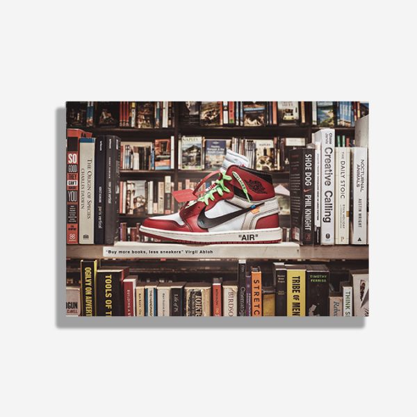 A4 print mockup - The image features a Nike Air Jordan 1 high with the off white collaboration. The sneaker is sat on a bookshelf surrounded by books. There is a plaque attached which says, ' Buy more books, less Sneakers'