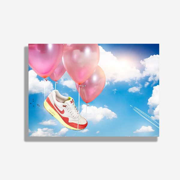 A4 print mockup- The image features a Nike Air Max 1 sneaker from the Nike Air Max day release. It is attached to four balloons and is floating through the sky.