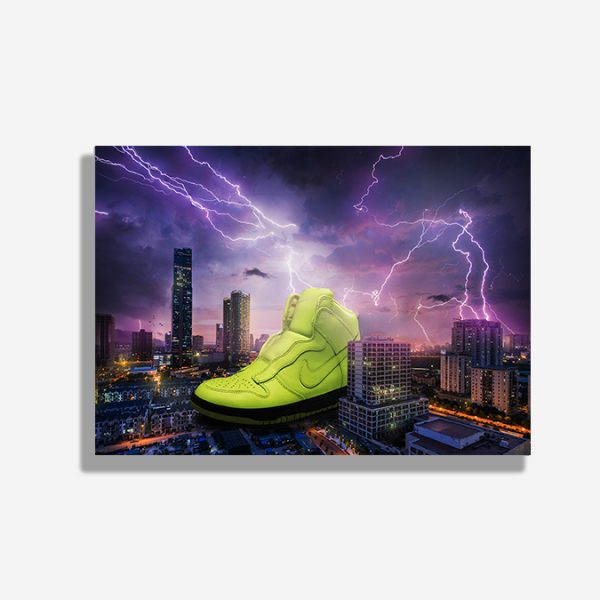A4 print mockup - The image features a Nike Lux Volt Dunk in collaboration with Sacai. The sneaker is shown as being giant and is placed in a city scape with lightning a dark skies.